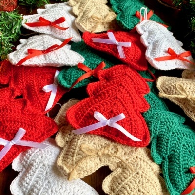 Decorações de Natal em croché com laços coloridos sobre mesa de madeira