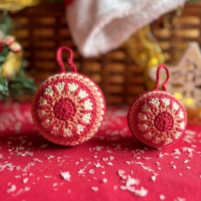 ornamentos de Natal redondos crocheted em vermelho, creme e rosa claro com padrão de pétalas