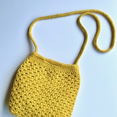 Mala amarela de crochet com alça fina sobre fundo branco