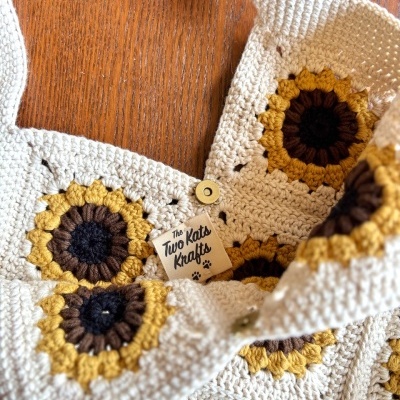 Top de croché creme com flores castanhas e amarelas e etiqueta The Two Kats Krafts