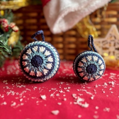 Enfeites de Natal em croché azul, branco e cinza sobre tecido vermelho.