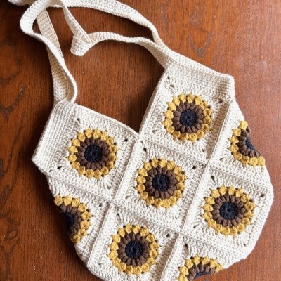 Bolsa de crochet com padrão de girassol em tons creme, castanho e amarelo.