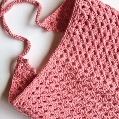 Top rosa de crochê com alças finas sobre fundo branco