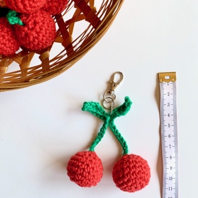 Porta-chaves de morangos em crochet com corrente metálica e fita métrica ao lado