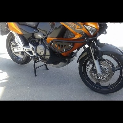 Motocicleta laranja e preta com suporte lateral parada no cimento