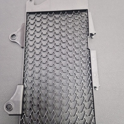 Grelha preta de plástico com padrão em ziguezague sobre superfície cinzenta