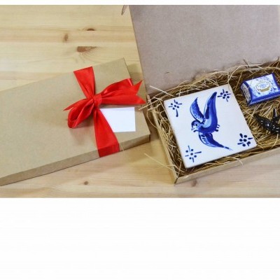 Conjunto de presente com azulejo decorativo numa caixa aberta e caixa fechada com fita vermelha