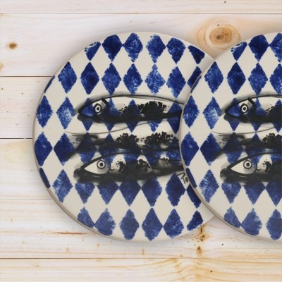 Dois pratos decorativos azuis e brancos com peixes pintados sobre mesa de madeira