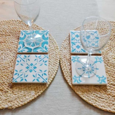 Bases para copos azuis e brancas com copos transparentes em bases de ráfia na mesa
