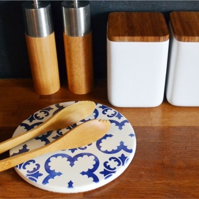 Utensílios de cozinha em madeira e metal com prato decorativo azul e branco sobre bancada de madeira