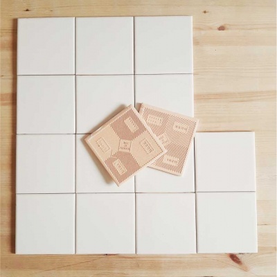 Azulejos cerâmicos brancos e bege com padrões geométricos sobre madeira