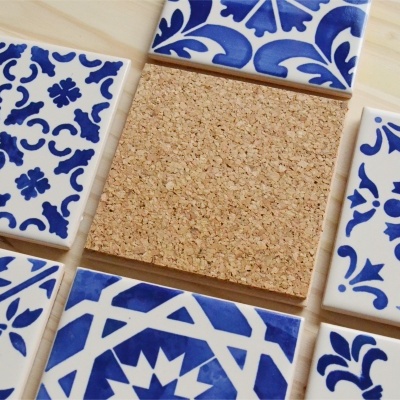 Azulejos quadrados azuis e brancos com bloco de cortiça no centro sobre superfície de madeira