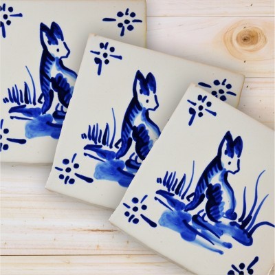 Azulejos cerâmicos brancos com desenho azul de coelho e padrões florais em fundo de madeira