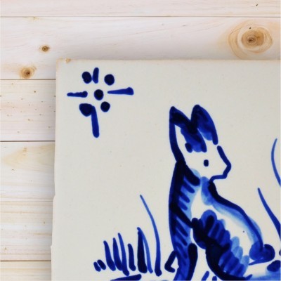 Azulejo cerâmico branco com pintura azul de gato e plantas