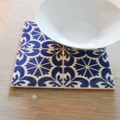 Conjunto de azulejos azuis e bege com tigela branca sobre superfície texturizada.