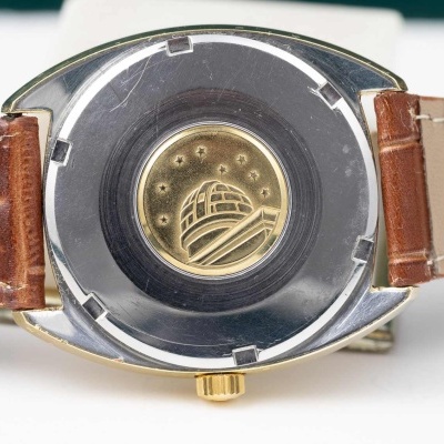 Relógio visto de trás com bracelete de couro castanho e mostrador metálico detalhado