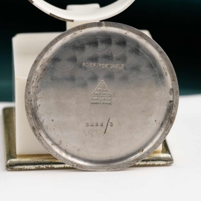 Fundo metálico redondo de relógio com inscrições gravadas sobre superfície branca