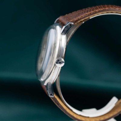 Relógio analógico com caixa metálica prateada e bracelete de couro castanho