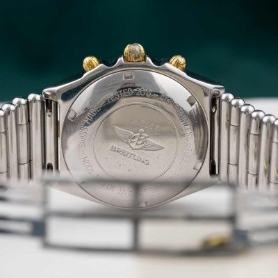 Relógio Breitling com bracelete de metal e botões dourados visto de trás