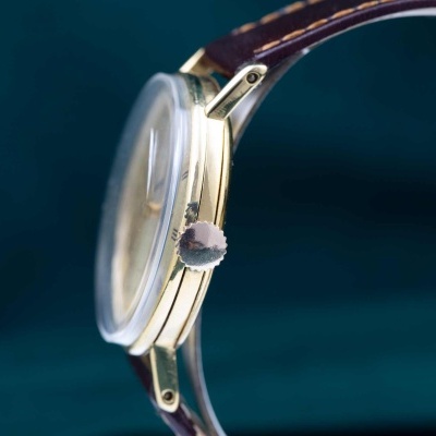 Relógio de pulso dourado com bracelete de couro castanho e vidro convexo