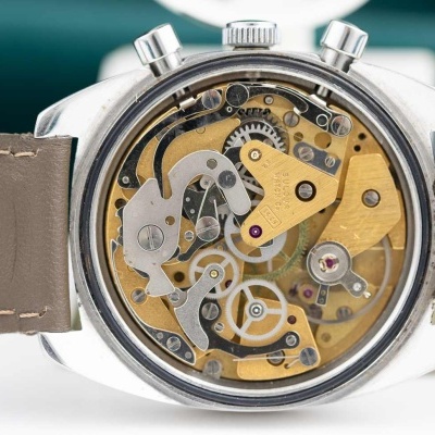 Relógio com caixa metálica e mecanismo interno visível, bracelete de pele castanha clara