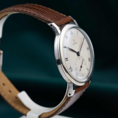 Relógio de pulso com bracelete de pele castanha e mostrador branco com numerais romanos.