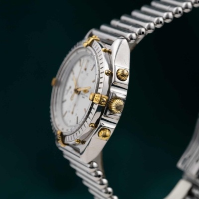 Relógio de pulso metálico com detalhes dourados e bracelete prateada