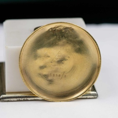 Botão redondo dourado com marcações gravadas na base branca