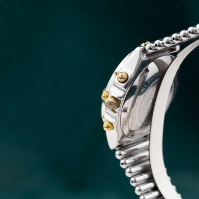 Relógio de pulso metálico prateado com detalhes dourados