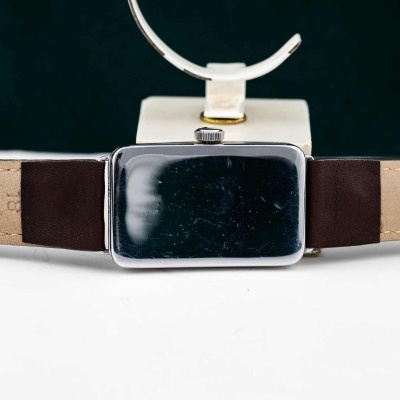 Relógio de pulso com caixa rectangular e bracelete em pele castanha.