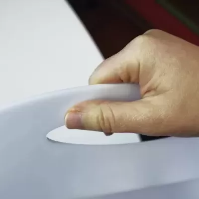 Mão a segurar alça oval recortada de objeto branco de plástico