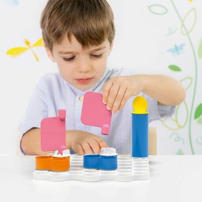 Criança a jogar com brinquedo de plástico colorido em base branca hexagonal