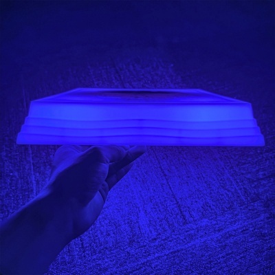 Luminária quadrada azul sendo segurada por uma mão, fundo texturizado azul