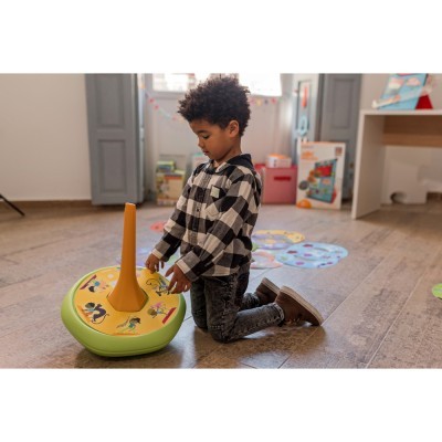 Criança a brincar com brinquedo redondo verde e amarelo com estrutura laranja