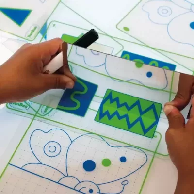 Mãos segurando régua transparente com estampas de borboletas e formas geométricas azuis e verdes