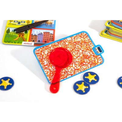 Tabuleiro de jogo com lupa vermelha, peças azuis com estrelas amarelas e cartas coloridas.