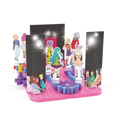 Brinquedo de passarela de moda com figuras de papel e cenário colorido.