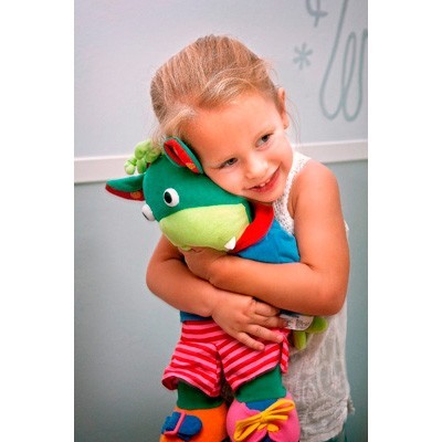 Criança abraçando boneco de pelúcia colorido em ambiente interno