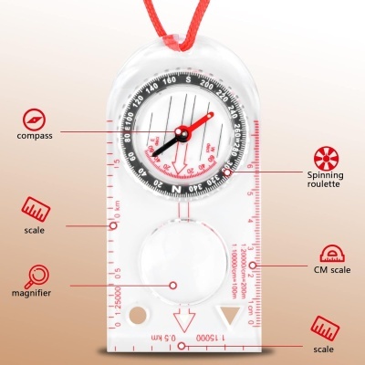Bússola transparente com ponteiros vermelhos e pretos, escala centimétrica, lupa, esfera giratória e cordão vermelho