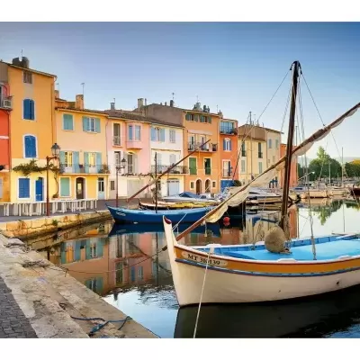Barco de madeira colorido ancorado em canal com casas coloridas refletidas na água