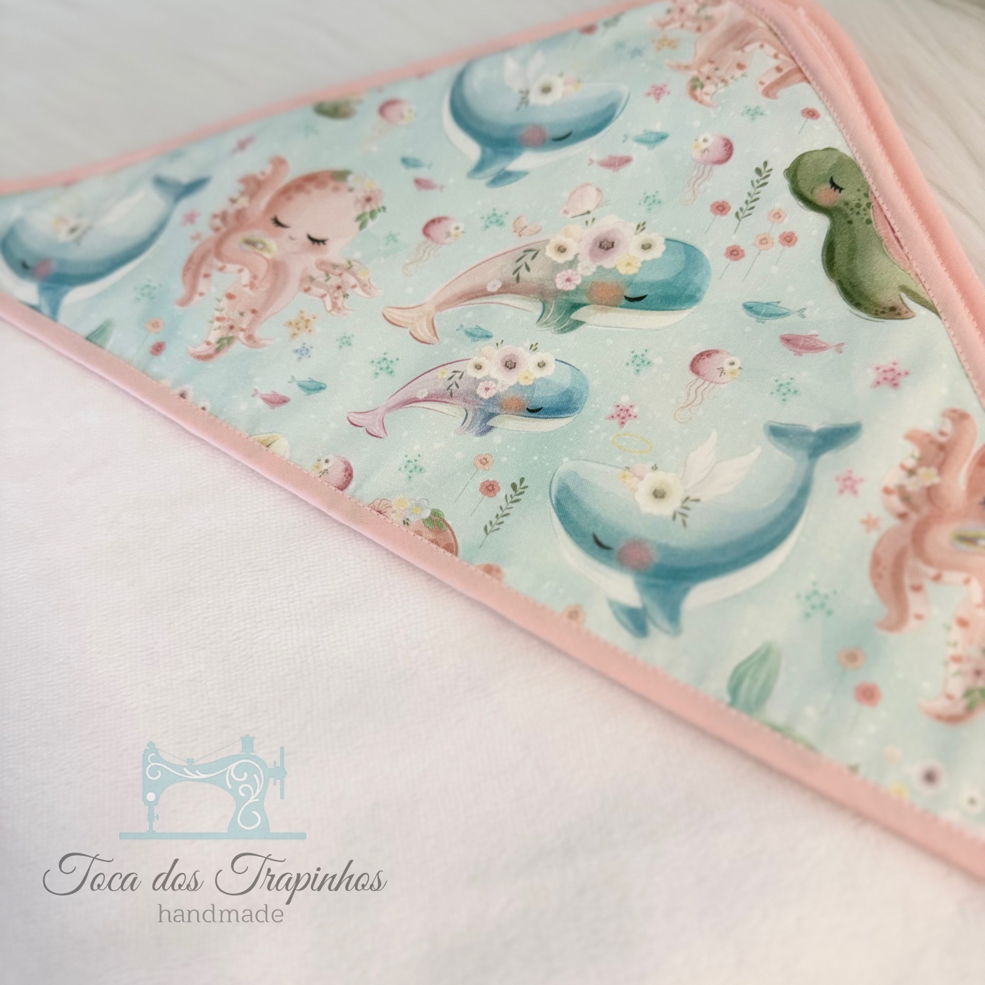 Toalha com canto em tecido estampado com animais marinhos e borda rosa clara