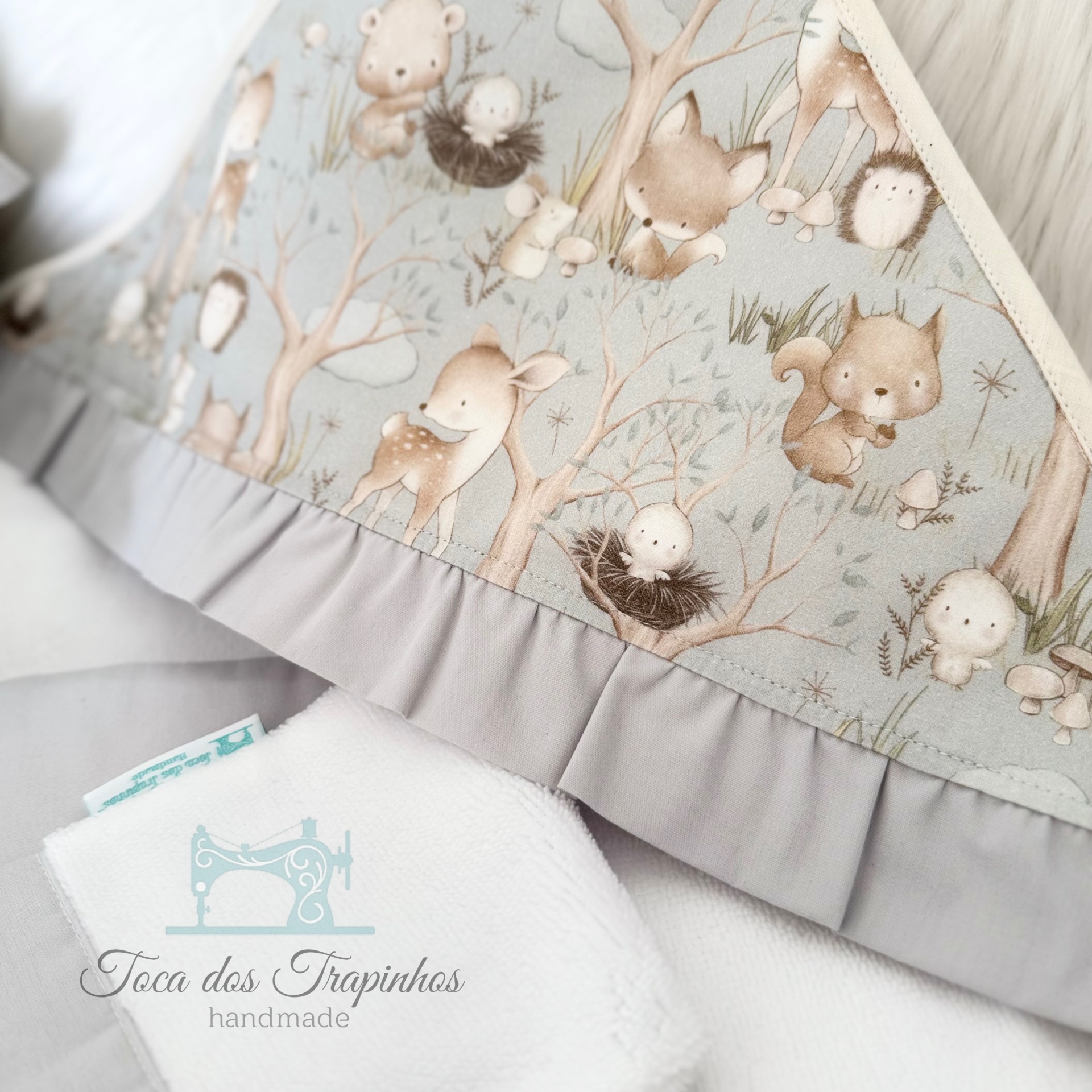 tecido com padrão de animais da floresta em tons pastéis com acabamento plissado cinza