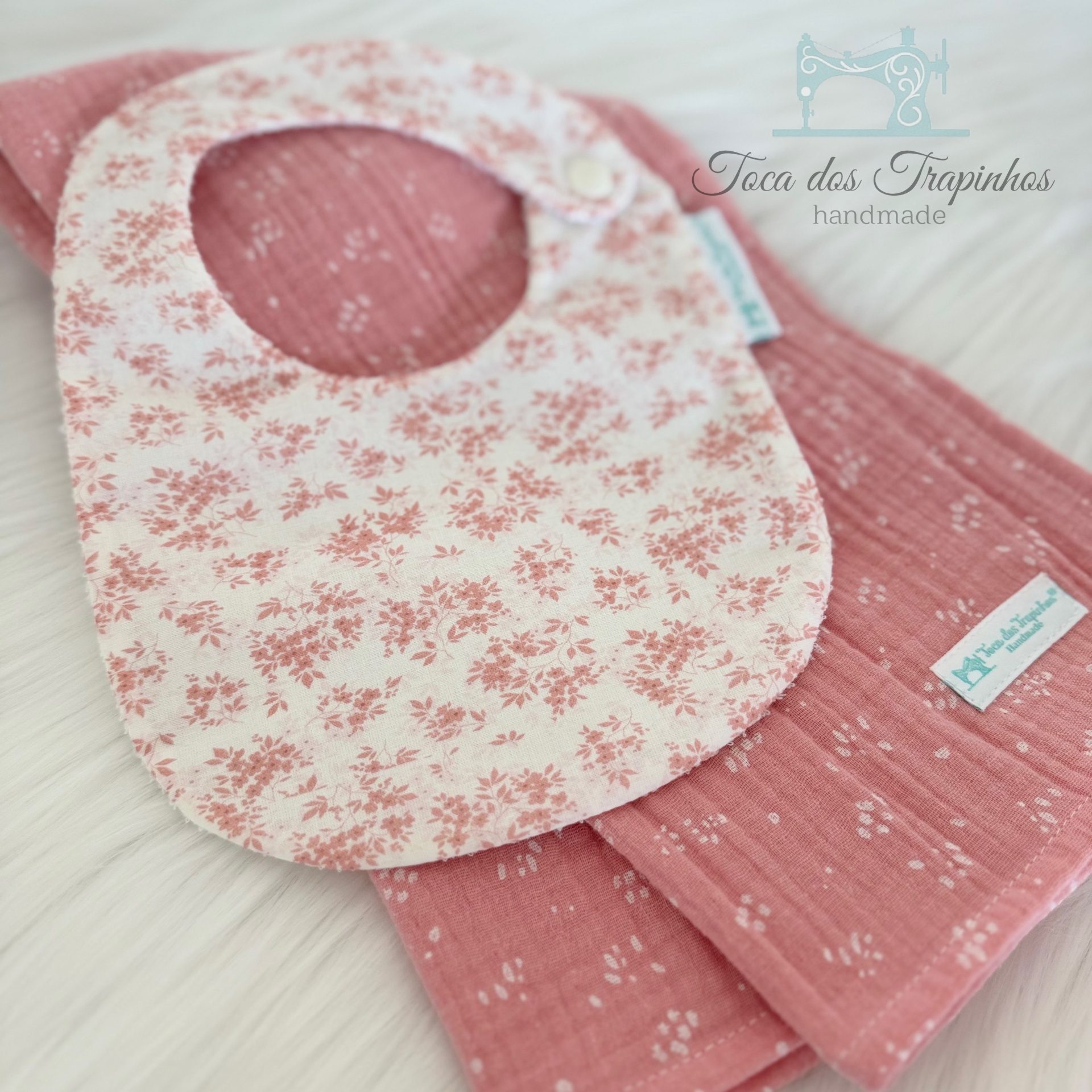 Babete branco com flores rosa e tecido rosa com padrões brancos