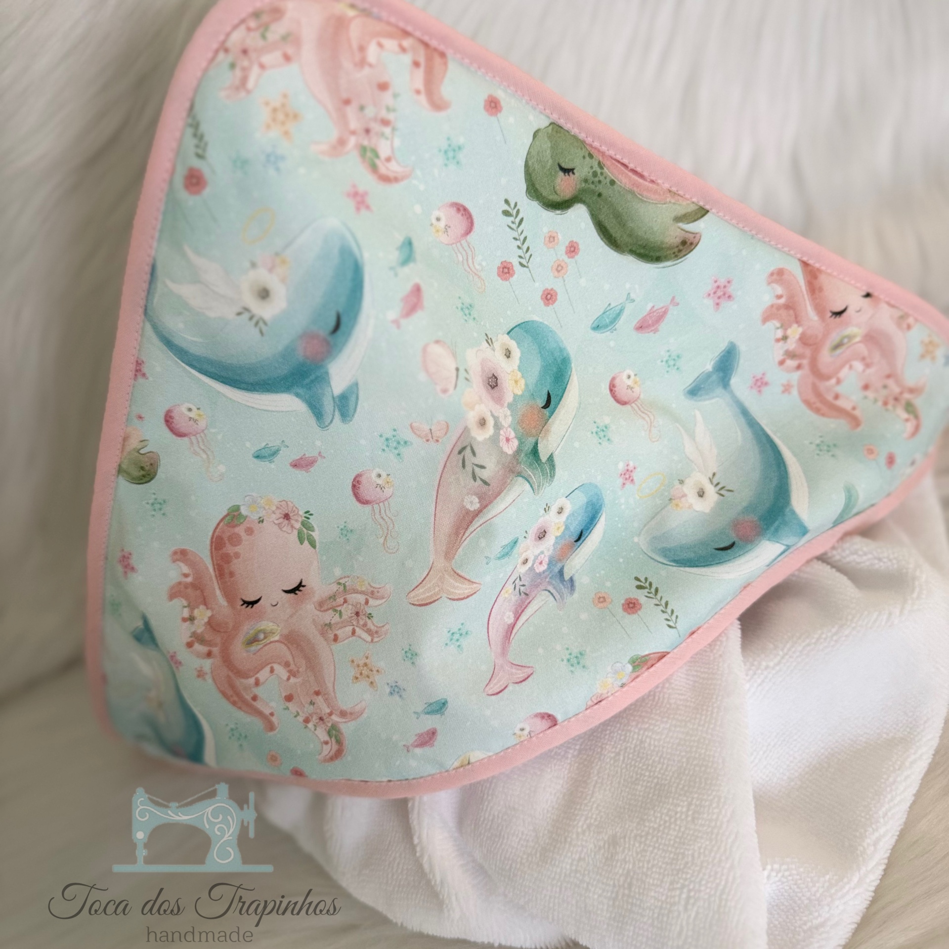 Toalha de bebé com capuz azul com desenhos de golfinhos e polvos cor de rosa