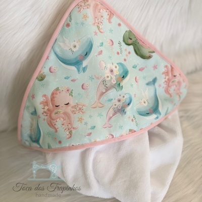 toalha de bebé com capuz azul claro com desenhos de polvos e golfinhos coloridos, tecido felpudo branco