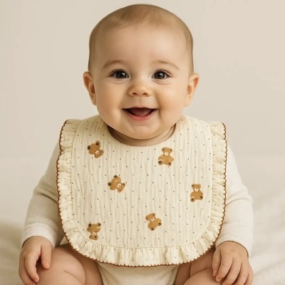 Babador creme com ursinhos castanhos usado por bebé sorridente