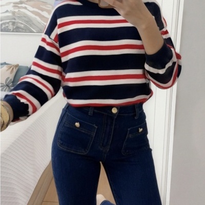 Pessoa com camisola riscada azul, branca e vermelha e calças de ganga azul escuro