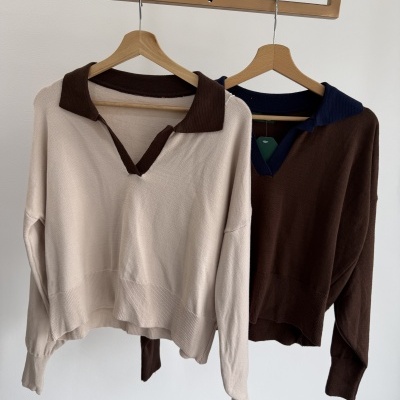 Dois suéteres de malha bege e castanho pendurados em cabides de madeira