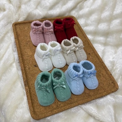 Sapatinhos de bebé em malha de várias cores com laços em placa de cortiça