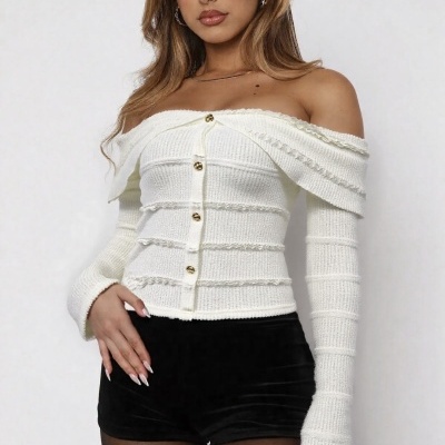 Mulher com blusa branca de malha ombro a ombro com botões dourados, calções pretos e collants pretos.